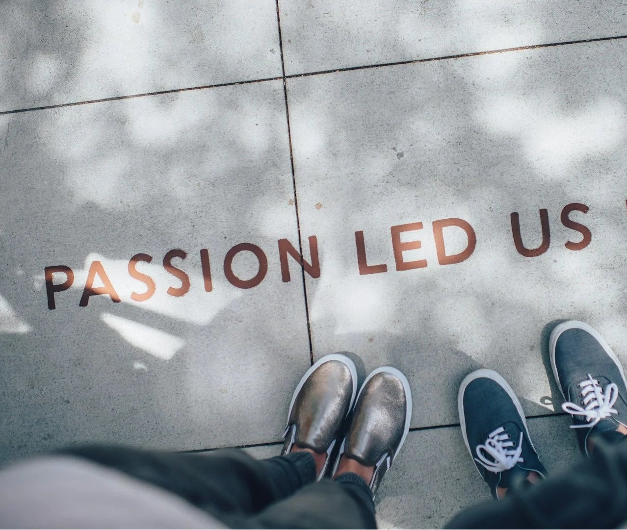 Pavimento illuminato con scritta "PASSION LED US HERE" e le scarpe di due persone visibili